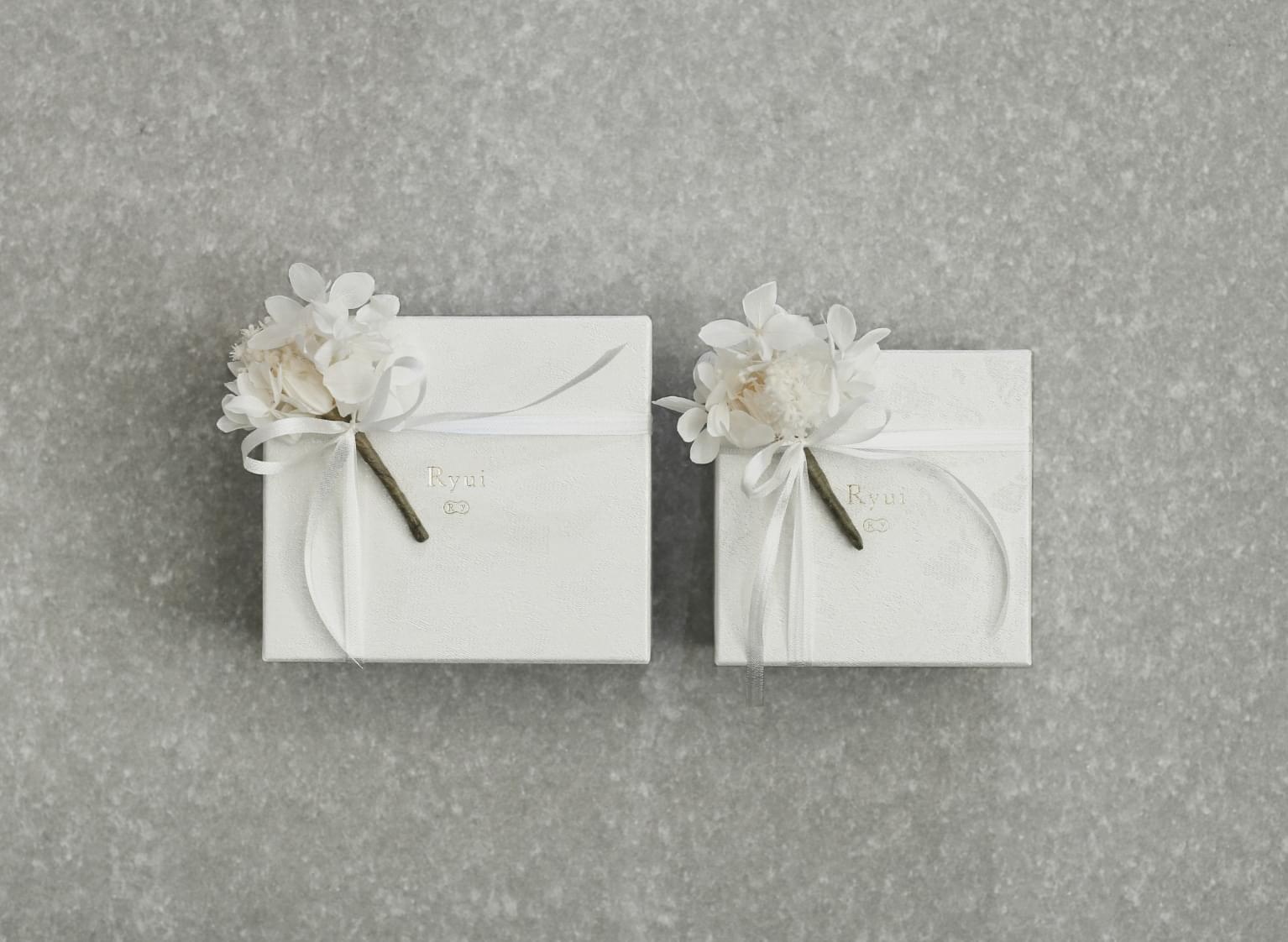 White boxes for two sizes of engagement rings with mini bouquets tied
